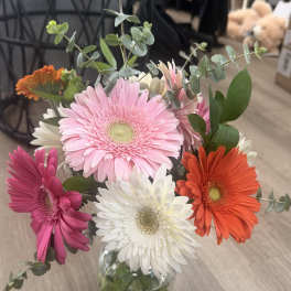 Mixed gerbera daisies in a glass vase with eucalyptus