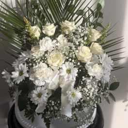 White floral arrangement with roses and daisies in a white container