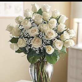 Arrangement of ivory roses with baby's breath in a clear glass vase