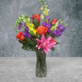 Colorful bouquet of roses, lilies, and stock in a glass vase
