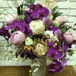 Purple orchids and pale peonies arranged in a tall vase