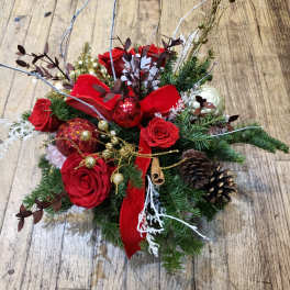 Christmas floral arrangement with red roses, pinecones, and ornaments