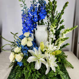 White lilies and roses with blue delphinium in a white vase