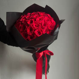 Bouquet of red roses wrapped in black paper with a red ribbon