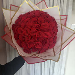 Large bouquet of red roses wrapped in pink and gold paper