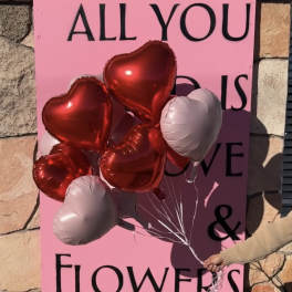 Heart-shaped balloons in red and white held in front of a pink sign