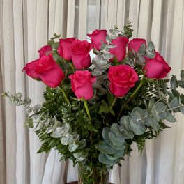 Hot pink roses in a clear glass vase with eucalyptus