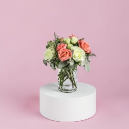 Pink and white roses arranged in a clear glass vase