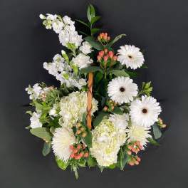 White floral wreath with gerbera daisies and hydrangeas on a dark background