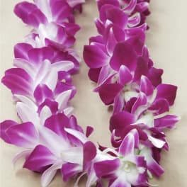 Purple and white orchid lei laid on a neutral surface