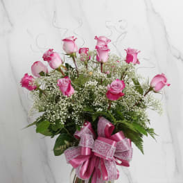 Pink roses in a clear glass vase with a large ribbon bow