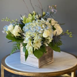 White and pale blue floral arrangement in a wooden box