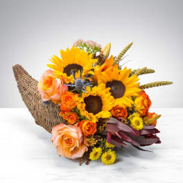 Basket arrangement with sunflowers, orange roses, and peach roses