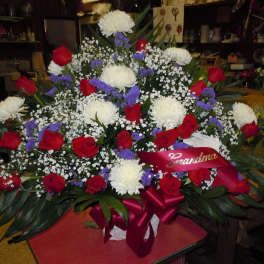 Large bouquet of red roses, white chrysanthemums, and purple filler flowers with a ribbon