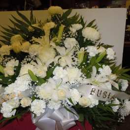 Large white funeral spray with lilies, carnations, and roses