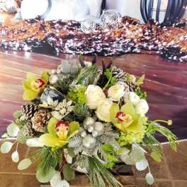 Mixed floral arrangement with white roses and yellow orchids in a low container