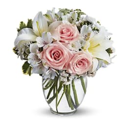Pink roses and white lilies arranged in a clear glass vase