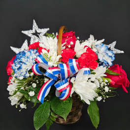 Basket of red, white, and blue flowers with star decorations and ribbon