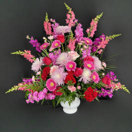 Large pink and red floral arrangement in a white vase