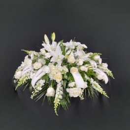 White floral spray with lilies and roses on a dark background