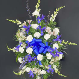 Standing floral spray with white and purple flowers and a blue ribbon