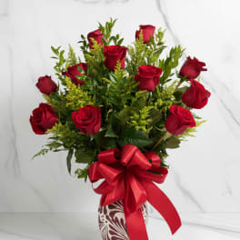 Red roses in a patterned vase with a large red ribbon