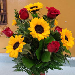 Bouquet of red roses and yellow sunflowers in a glass vase