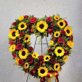 Heart-shaped wreath of sunflowers and red roses on a stand