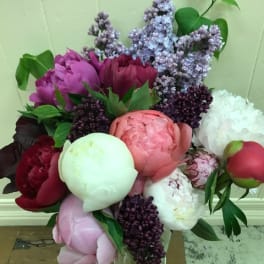 Bouquet of peonies and lilacs in a clear glass vase