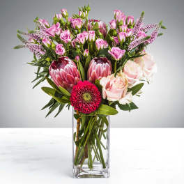 Pink roses and protea in a clear glass vase