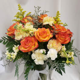 Bouquet of orange roses and pale carnations in a glass vase