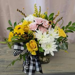 Bouquet of pink and yellow roses with white daisies in a glass vase