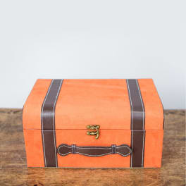 Orange suitcase-shaped box with brown straps and a latch