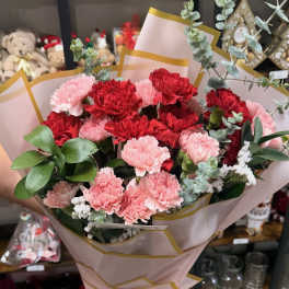 Bouquet of red and pink carnations wrapped in blush paper
