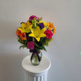Colorful bouquet of lilies, daisies, and carnations in a glass vase