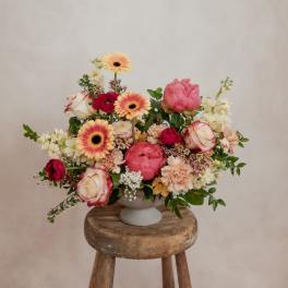 Mixed pink and cream bouquet in a white pedestal vase