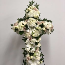 Cross-shaped floral spray with white lilies, hydrangeas, and pale roses