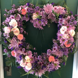 Heart-shaped floral wreath with pink and purple flowers on a green door