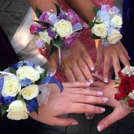 Hands wearing rose corsages in red, white, blue, and lavender