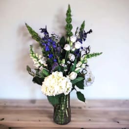 White and blue floral arrangement in a glass vase