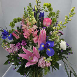 Mixed bouquet with pink lilies, blue irises, and pink roses in a glass vase