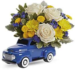 Blue toy truck holding a bouquet of white, yellow, and purple flowers
