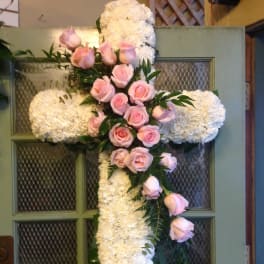 White floral cross with pink roses on a door