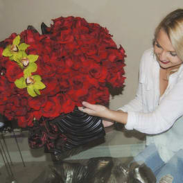 Large red rose arrangement with yellow orchids in a black vase