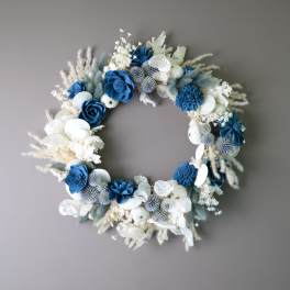 Blue and white floral wreath with dried accents on a gray wall