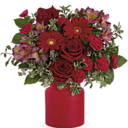 Red roses and pink flowers in a red vase