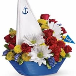 Boat-shaped floral arrangement with red, white, and yellow flowers and a small sail