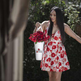 Woman holding a white bucket of red roses