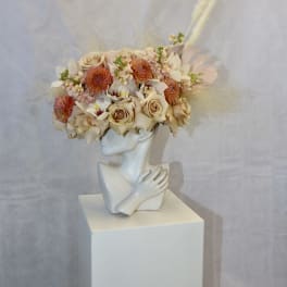 Floral crown on a white bust with cream and peach blooms