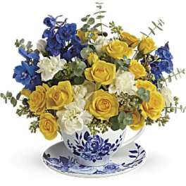 Yellow and blue rose bouquet in a teacup and saucer